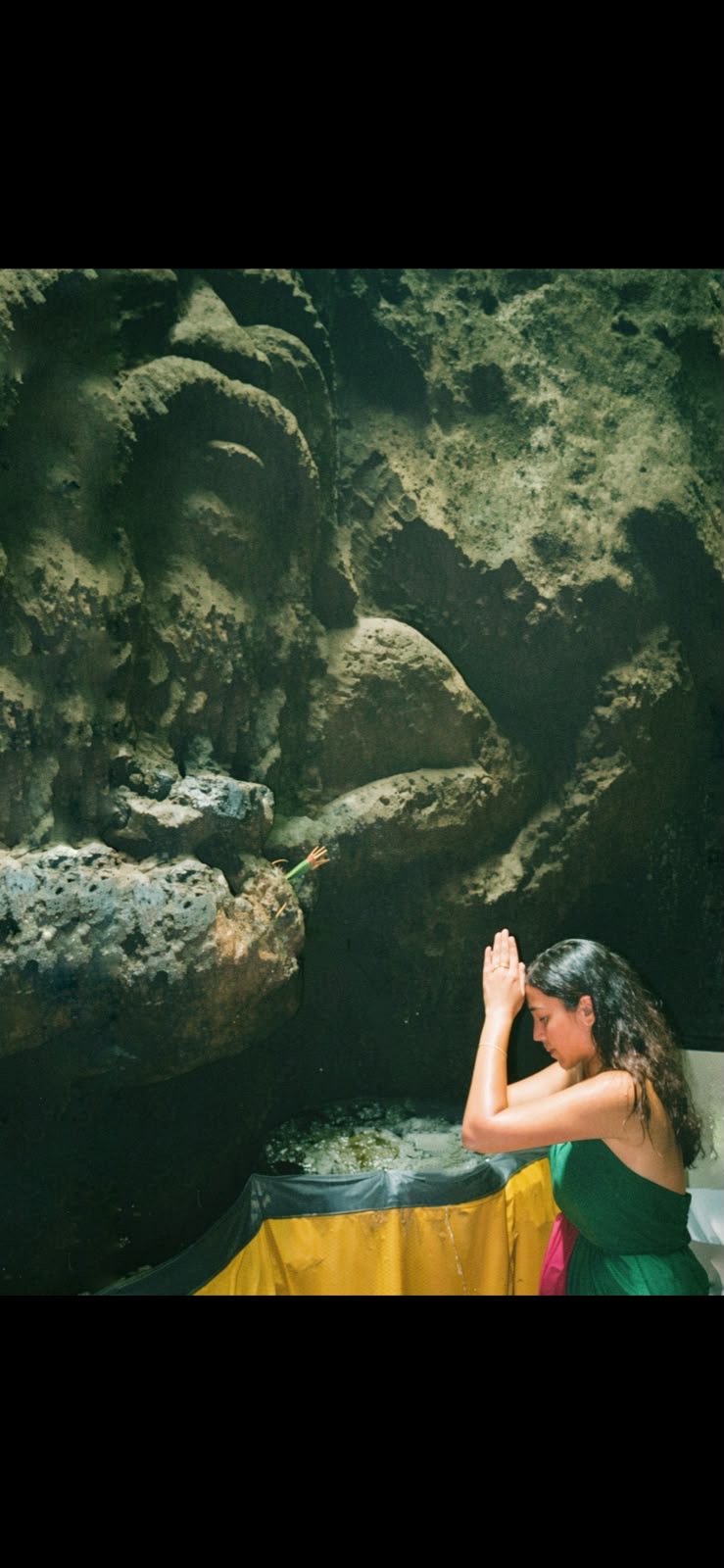 Tara in prayer beside a stone water feature in a contemplative sacred setting