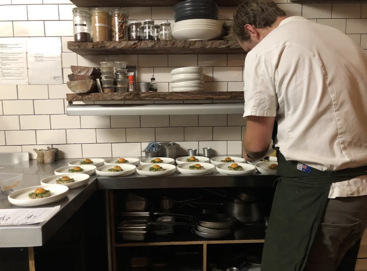 Chef Nick Gardner plating a series of dishes in a professional kitchen