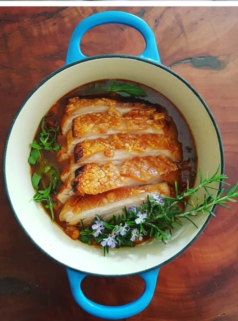 Braised chicken served in a blue enamel pan with herbs