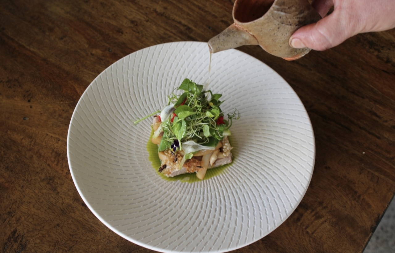 Seasonal plated course finished with sauce at the table